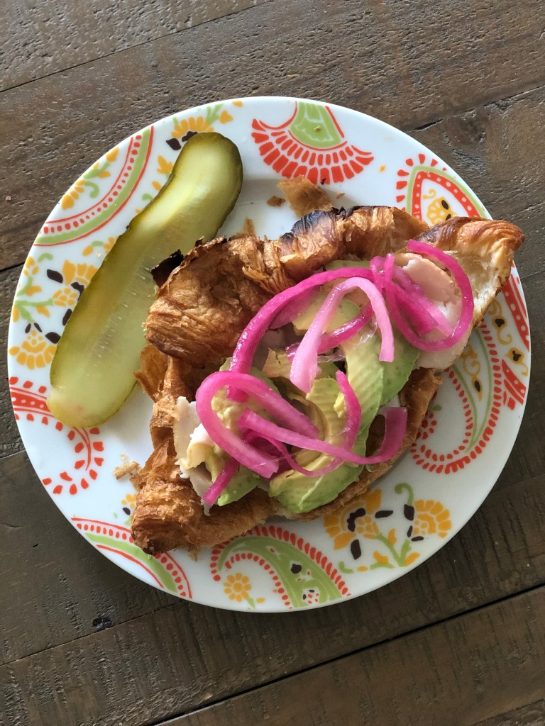 croissant with pickled red onions and avocado